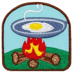 A frying pan with an egg is above a burning fire.