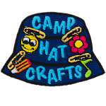 A blue camp hat has little crafts pinned to it. The text Camp Hat Crafts is embroidered on the side.