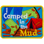 A person wearing bright green boots splashes in a mud puddle. The words I Camped in the Mud are overlayed atop the image.