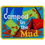 A person wearing bright green boots splashes in a mud puddle. The words I Camped in the Mud are overlayed atop the image.