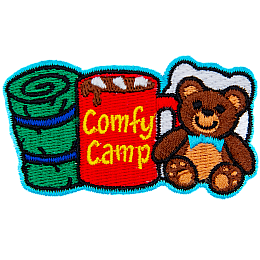 From left to right is a sleeping bag, a mug of coco with the words 'Comfy Camping' on the side, and a teddy bear with a pillow behind it.