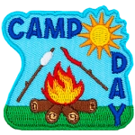 A marshmallow and hotdog roast over a fire. The words Camp Day are above and on the right.