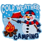 A camping snowman roasts a marshmallow over a campfire. The badge reads Cold Weather Camping.