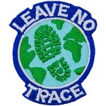 Earth with a boot print across the ocean. The words Leave No Trace are written around the outside.