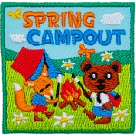An anthropomorphic bear and a fox roast marshmallows over a campfire. A tent is behind them in an open meadow. Spring Campout is stitched above.