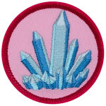 A blue, pointed crystal sits on a soft pink background.