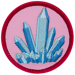 A blue, pointed crystal sits on a soft pink background.