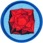 A red garnet is in the centre of a circular blue badge.