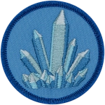 A blue, pointed crystal sits on a light blue background.