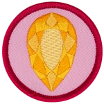 A golden citrine is in the centre of a circular pink badge.
