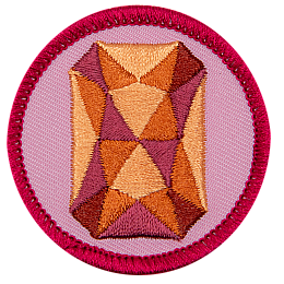 An orange sapphire is in the centre of a circular pink badge.