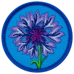A purple cornflower is in the centre of a blue, circular patch.