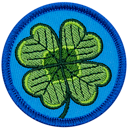 This circular patch displays a four-leaf shamrock on a background of blue.