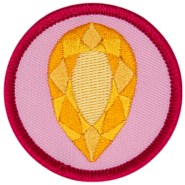 A golden citrine is in the centre of a circular pink badge.