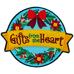 A holiday wreath has a yellow ribbon over it that reads Gifts From The Heart.