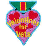 A heart-shaped badge with the words Valentines For Vets in the center.