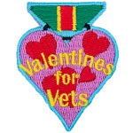 A heart-shaped badge with the words Valentines For Vets in the center.