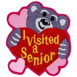 A teddy bear hugs a heart that says I Visited A Senior.
