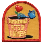 The words Random Acts of Kindness are on a clay pot with a heart-shaped flower in it.