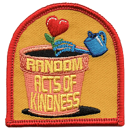 The words Random Acts of Kindness are on a clay pot with a heart-shaped flower in it.