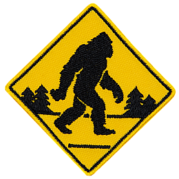 A yellow road sign with a Sasquatch crossing the road.