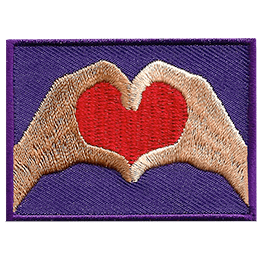 Two hands form a red heart on a purple background. The left hand is brown, and the right is beige.