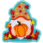 A gnome holds a ripe pumpkin. The gnome is covered in leaves and wears a red and yellow polka-dotted hat.