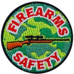 This light and dark green camouflage patch depicts a rifle with the words Firearms Safety embroidered in red and white.