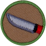 This one-inch circle badge depicts a sharp-bladed knife with a red handle.