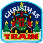 The front of a train is decorated with a wreath and lights. The words Christmas Train are above and below. Two trees frame either side.