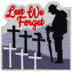 A soldier stands with his head bowed in front of several crosses. The words Lest We Forget are in the sky.