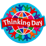 A colourful globe is circled by rainbow-coloured people holding hands. A banner that says Thinking Day is across the middle.