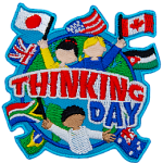 Three cheering people hold up flags of the world on the globe. The words Thinking Day are across the middle.