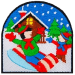 A kid sleds down a kill while another kid stands to the side and cheers. In the background are a cabin and pine trees.