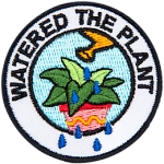 A plant is being watered with a yellow watering can. The words Watered The Plant are arched around it.
