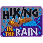 The words Hiking In The Rain surround two brown shoes walking up a hill in the rain.