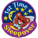 A teddy bear sleeps under a starry night sky. 1st Time Sleepover is stitched in a circle around them.