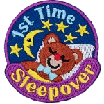 A teddy bear sleeps under a starry night sky. 1st Time Sleepover is stitched in a circle around them.