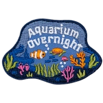 A fish and a sea turtle swim through a coral reef under the words Aquarium Overnight.