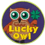 A brown owl with big green eyes holds a four-leaf clover in his wing. The words Lucky Owl is written in yellow near the bottom of the patch.