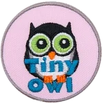 A small black owl with a white belly stares off into the distance. The words Tiny Owl are written in blue text near the bottom of the patch.