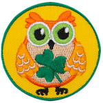 This orange owl holds a three-leaf clover in its wings.