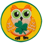 This orange owl holds a three-leaf clover in its wings.