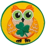 This orange owl holds a three-leaf clover in its wings.