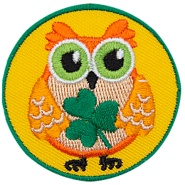 This orange owl holds a three-leaf clover in its wings.