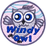 This grey owl dances in the wind. Whispy blue lines in the background indicate a breeze is blowing. The text Windy Owl is at the bottom.