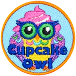 The words Cupcake Owl are printed across this owl. A pink and white swirl of frosting is on its head, and its feathers resemble sprinkles.