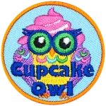 The words Cupcake Owl are printed across this owl. A pink and white swirl of frosting is on its head, and its feathers resemble sprinkles.