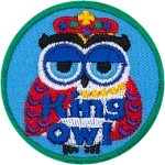 This regal owl has a crown on its head and its wings look like it's wearing a rich red cape.