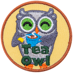 A grey owl smiles and holds a steaming cup of tea with the tea bag still in it. At the bottom of this crest are the words Tea Owl.